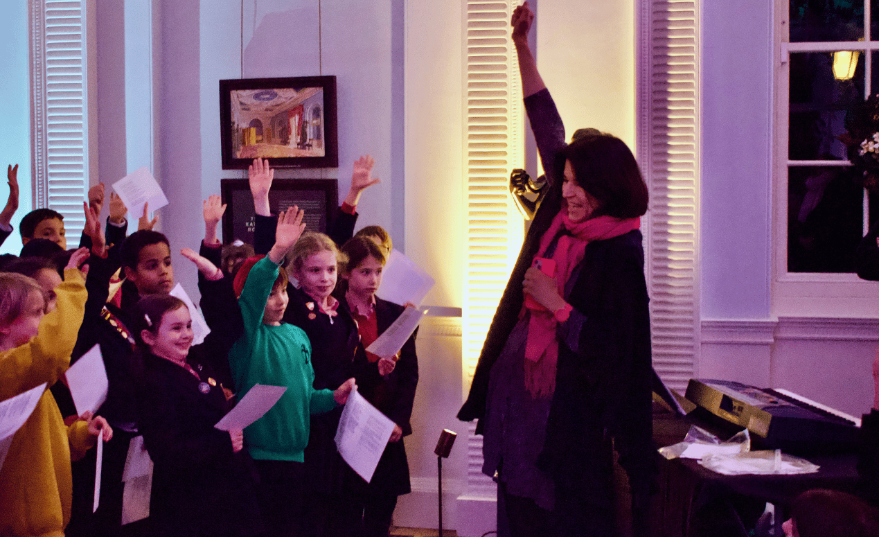 Excited children raising hands in an evening performance, engaging in activities at Pitzhanger Manor.